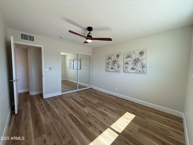 unfurnished bedroom featuring visible vents, a ceiling fan, wood finished floors, a closet, and baseboards