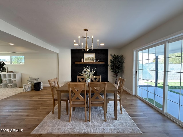 dining area with a chandelier, a healthy amount of sunlight, baseboards, and wood finished floors