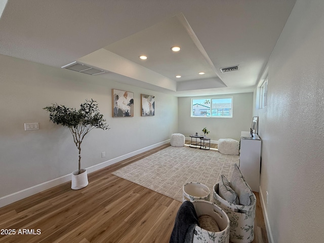 sitting room with wood finished floors, baseboards, visible vents, a tray ceiling, and recessed lighting