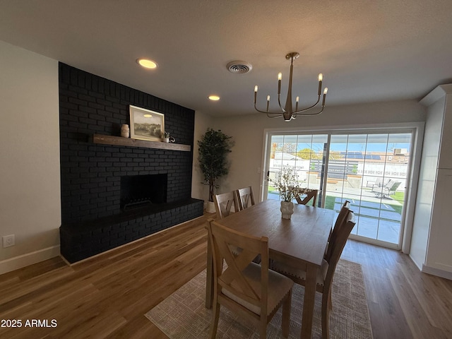 dining room with a notable chandelier, a fireplace, visible vents, and light wood-type flooring