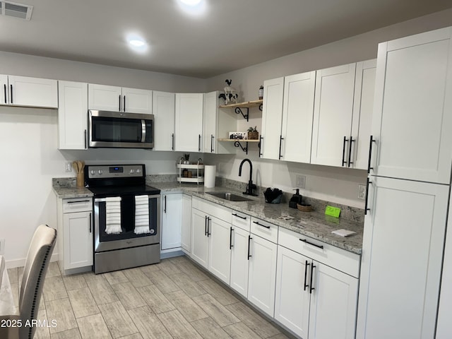 4602 N 47th Ave N, Phoenix, AZ 85031 - kitchen with stainless steel appliances, a sink, open shelves, white cabinets, and light stone counters