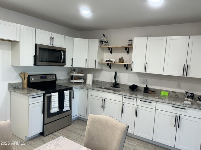 4602 N 47th Ave N, Phoenix, AZ 85031 - kitchen with appliances with stainless steel finishes, a sink, white cabinetry, light stone countertops, and light wood-style floors