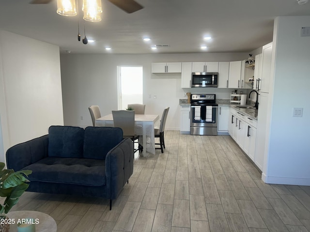 4602 N 47th Ave N, Phoenix, AZ 85031 - kitchen with appliances with stainless steel finishes, a sink, light wood-type flooring, white cabinetry, and open floor plan