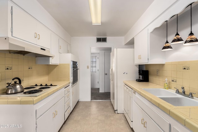 kitchen with visible vents, under cabinet range hood, white cabinets, white appliances, and a sink