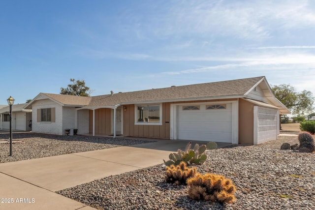 ranch-style home featuring concrete driveway, brick siding, a garage, and a shingled roof