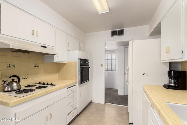 kitchen with white appliances, white cabinetry, and tile counters