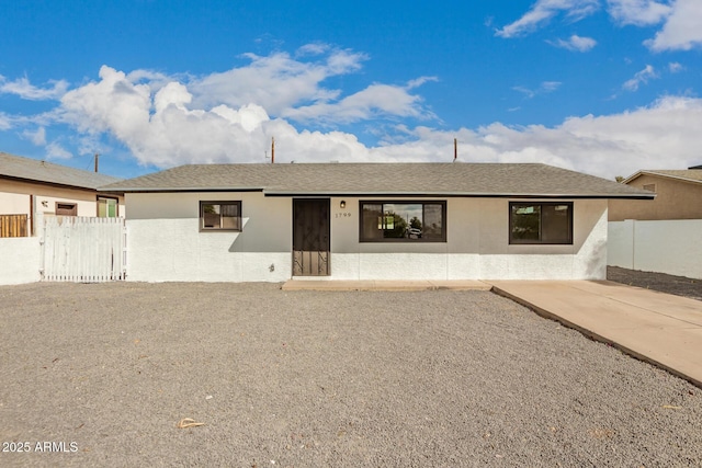 view of front of house with a shingled roof, fence, and stucco siding