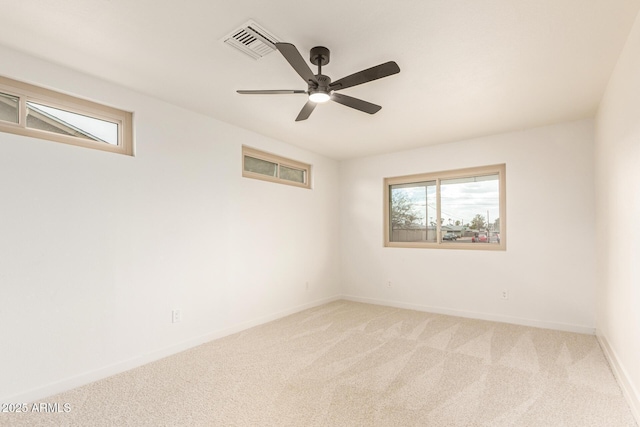 spare room featuring baseboards, a ceiling fan, visible vents, and light colored carpet