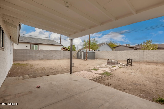 view of yard with an outbuilding, a patio area, a fenced backyard, and a shed