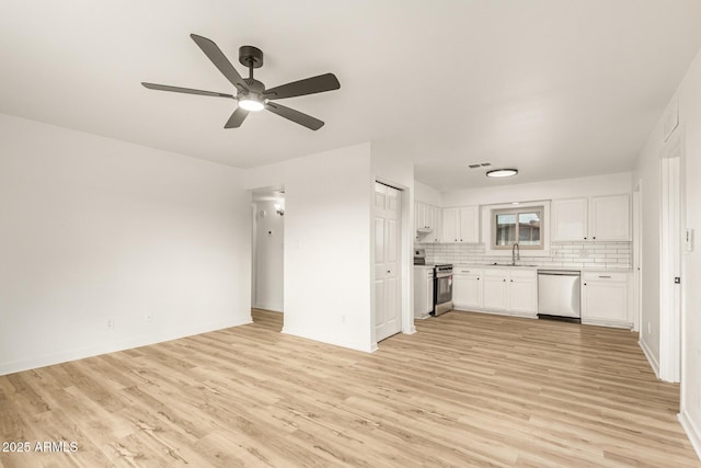 kitchen featuring stainless steel appliances, a sink, white cabinetry, light countertops, and backsplash