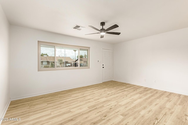 spare room featuring light wood-style floors, visible vents, baseboards, and a ceiling fan