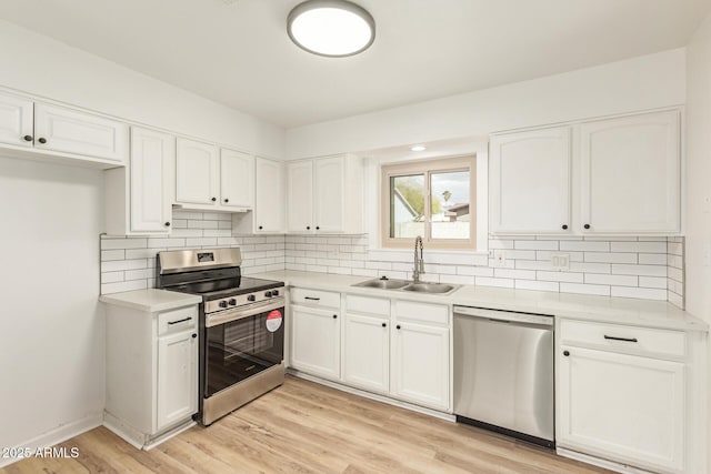 kitchen featuring stainless steel appliances, a sink, white cabinetry, light wood-style floors, and decorative backsplash