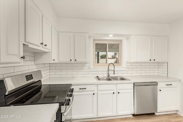 kitchen with light countertops, appliances with stainless steel finishes, light wood-style floors, white cabinetry, and a sink