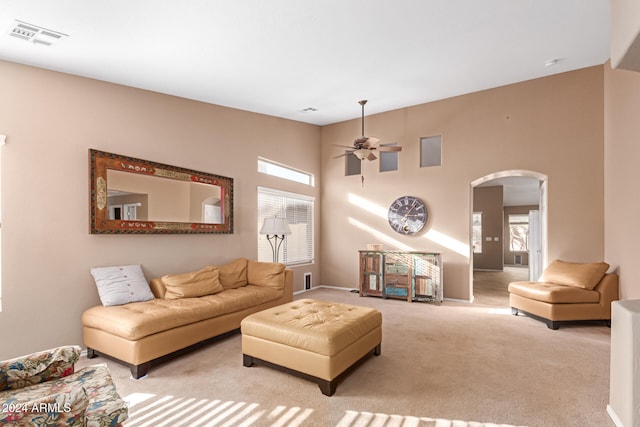 living room with ceiling fan, a high ceiling, and light colored carpet