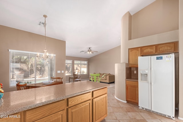 kitchen featuring ceiling fan with notable chandelier, light stone counters, tasteful backsplash, white refrigerator with ice dispenser, and decorative light fixtures