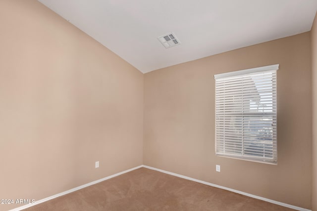 spare room featuring lofted ceiling and carpet