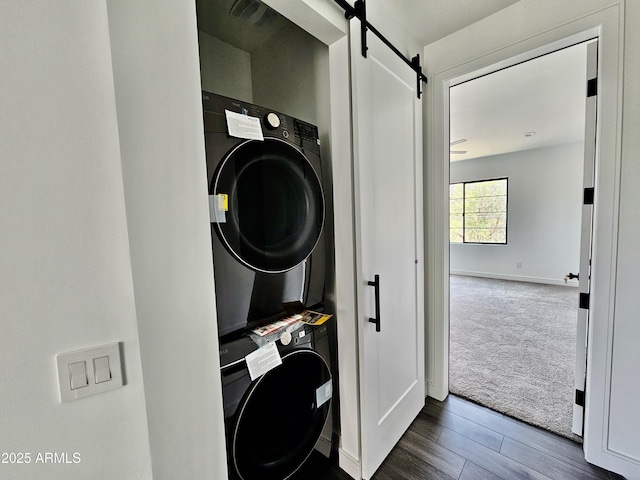 1401 S Rita Ln, Tempe, AZ 85281 - washroom with estacked washer and dryer, a barn door, dark colored carpet, and dark wood finished floors