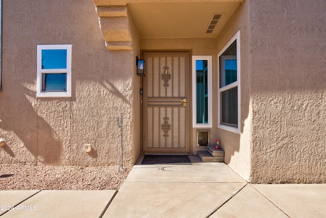 doorway to property with visible vents and stucco siding