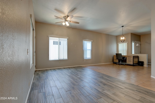 interior space with ceiling fan with notable chandelier, wood finished floors, and baseboards