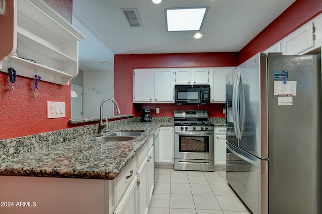 kitchen with a peninsula, a sink, visible vents, appliances with stainless steel finishes, and dark stone countertops