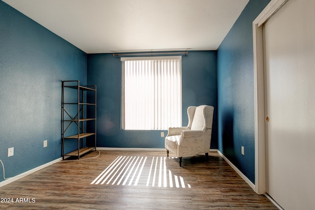 unfurnished room with baseboards, wood finished floors, and a textured wall