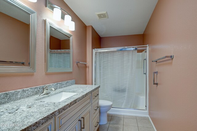 full bathroom with toilet, vanity, visible vents, tile patterned floors, and a stall shower