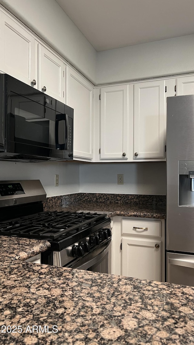 kitchen featuring dark stone counters, appliances with stainless steel finishes, and white cabinetry