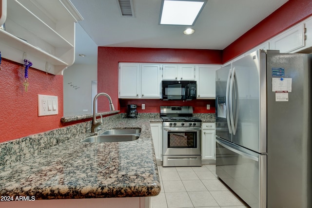 kitchen featuring visible vents, light stone counters, a peninsula, stainless steel appliances, and a sink