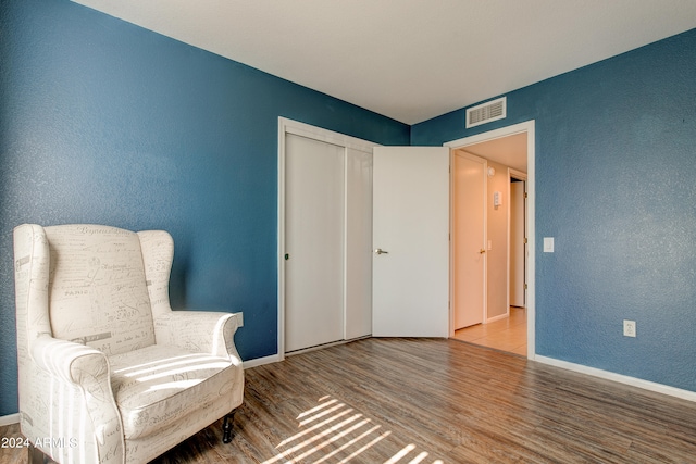 unfurnished room with baseboards, visible vents, wood finished floors, and a textured wall