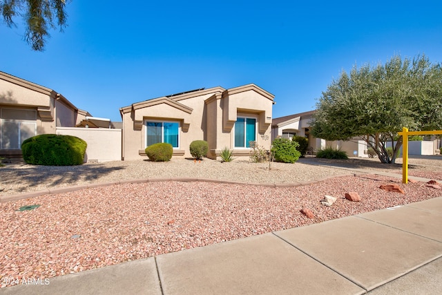 view of front of house with solar panels, fence, and stucco siding