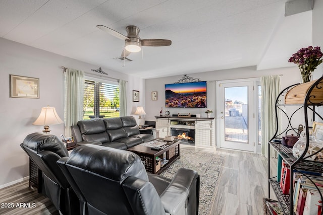 7738 N 185th Ave, Waddell, AZ 85355 - living room featuring ceiling fan, visible vents, baseboards, wood finished floors, and a lit fireplace