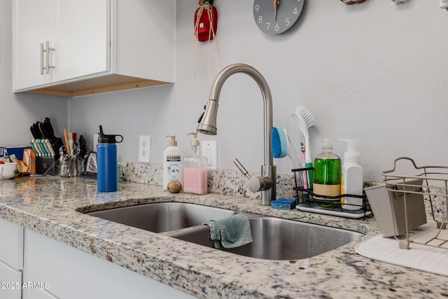 7738 N 185th Ave, Waddell, AZ 85355 - room details with light stone counters, a sink, white cabinetry, and a fire extinguisher