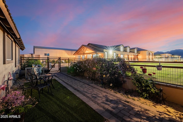 7738 N 185th Ave, Waddell, AZ 85355 - patio terrace at dusk featuring a yard, fence, and a gate