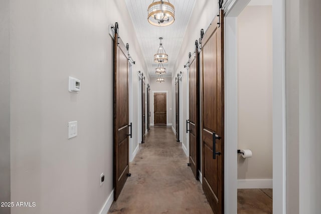 7738 N 185th Ave, Waddell, AZ 85355 - corridor with concrete flooring, baseboards, a notable chandelier, and a barn door