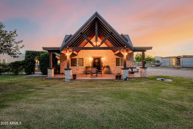 7738 N 185th Ave, Waddell, AZ 85355 - back of house at dusk featuring a lawn, a patio, fence, and stone siding