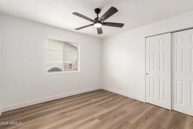 unfurnished bedroom with ceiling fan, a closet, and hardwood / wood-style floors