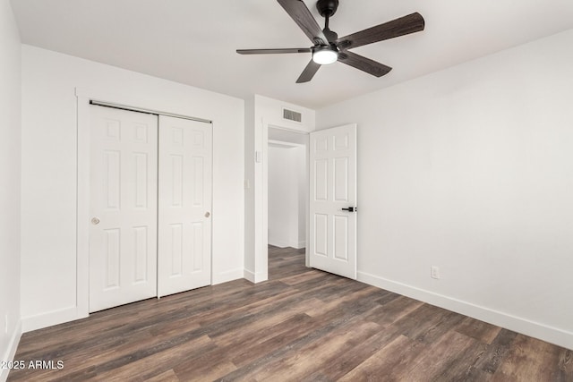 unfurnished bedroom with ceiling fan, a closet, and dark wood-type flooring