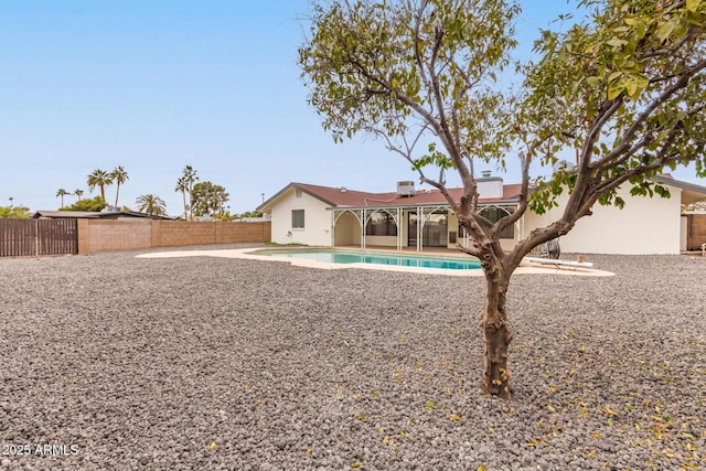 rear view of property featuring a patio and a fenced in pool