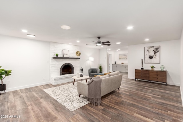 living room featuring ceiling fan, a fireplace, and dark wood-type flooring