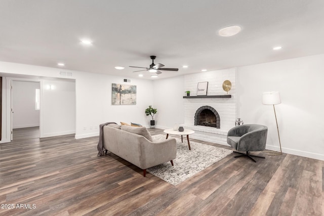 living room with a fireplace, dark hardwood / wood-style flooring, and ceiling fan