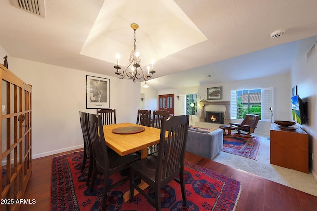 3417 E Mission Ln E, Phoenix, AZ 85028 - dining space featuring hardwood / wood-style floors, a chandelier, a warm lit fireplace, baseboards, and a tray ceiling