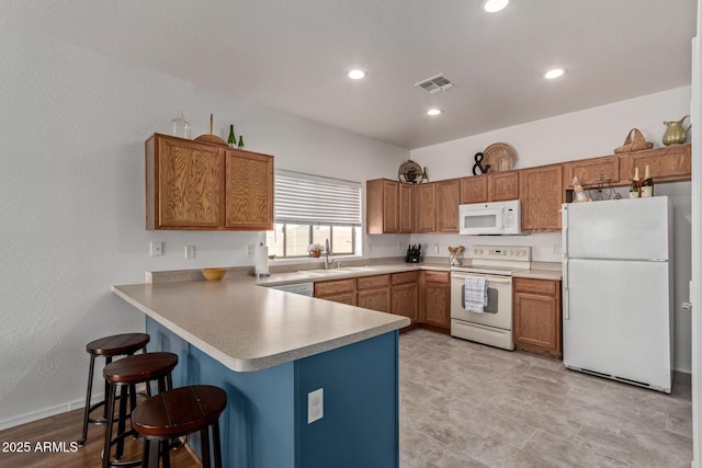 15246 N 138th Ln, Surprise, AZ 85379 - kitchen with visible vents, a sink, white appliances, a peninsula, and brown cabinetry