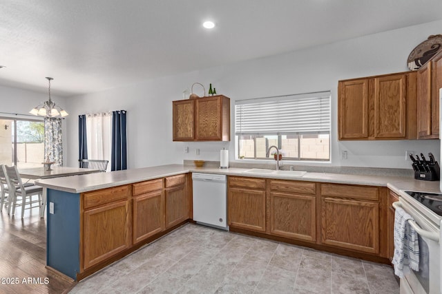 15246 N 138th Ln, Surprise, AZ 85379 - kitchen with brown cabinets, white appliances, a sink, a peninsula, and a chandelier