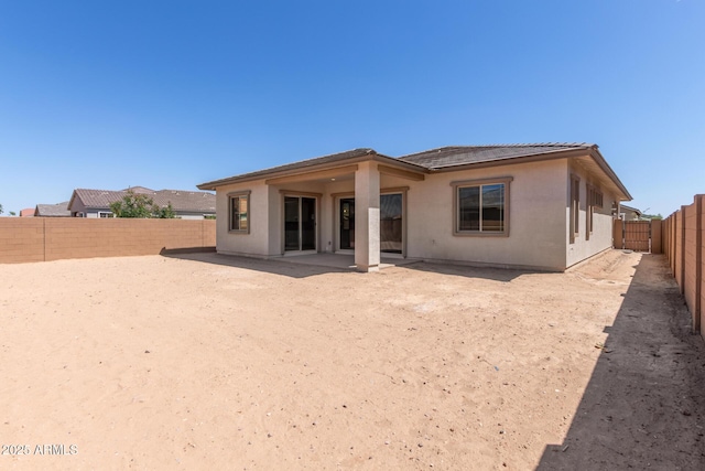 rear view of property with stucco siding, a tile roof, and a fenced backyard