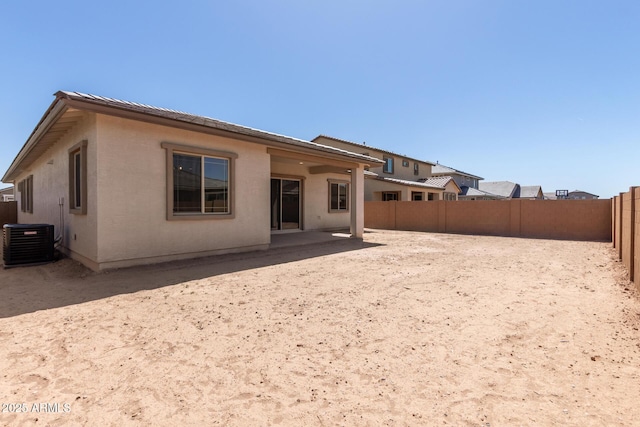 back of house with central AC unit, stucco siding, a fenced backyard, and a patio area
