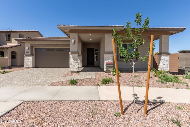 view of front facade featuring driveway, stucco siding, stone siding, and a garage