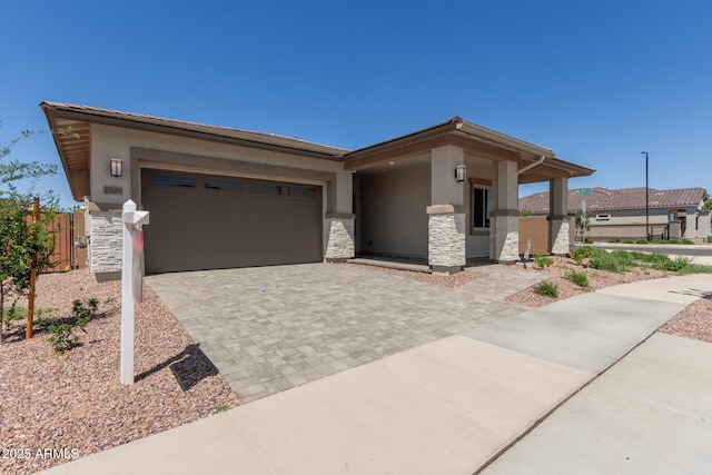 prairie-style house featuring a garage, stucco siding, decorative driveway, and stone siding