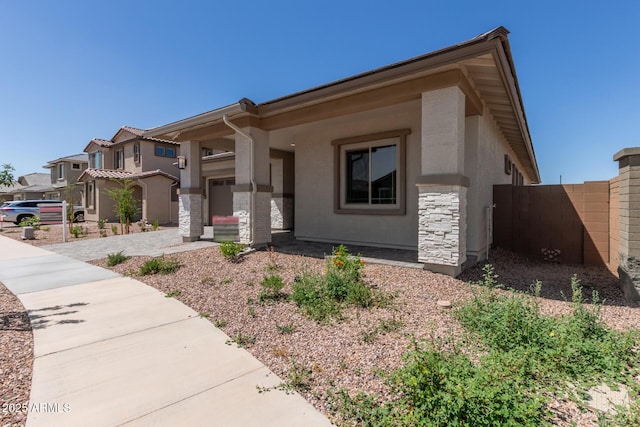 view of front of home with stone siding, stucco siding, and fence