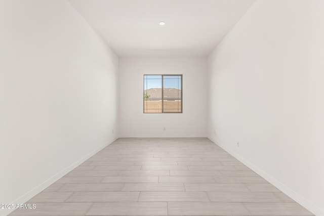spare room featuring baseboards and light wood-style flooring