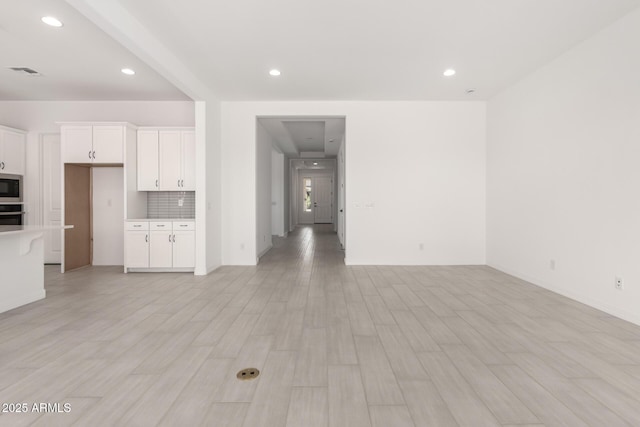 unfurnished living room featuring baseboards, visible vents, light wood-type flooring, and recessed lighting
